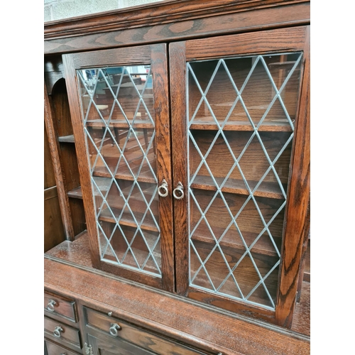 495 - A Jaycee oak dresser with two upper glazed doors, nine drawers and two lower cupboard doors - measur... 