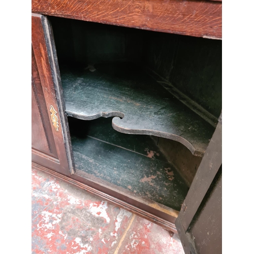 497 - A George III oak flat front corner cabinet with two upper doors, three internal shelves, two lower d... 