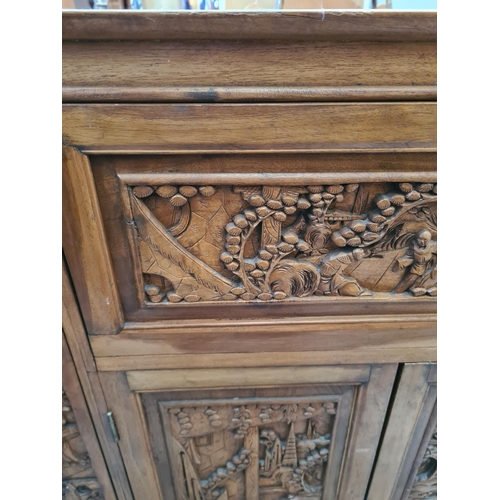 504 - An oriental carved teak concealed cocktail cabinet with hinged lid, eight place bottle holder, two l... 