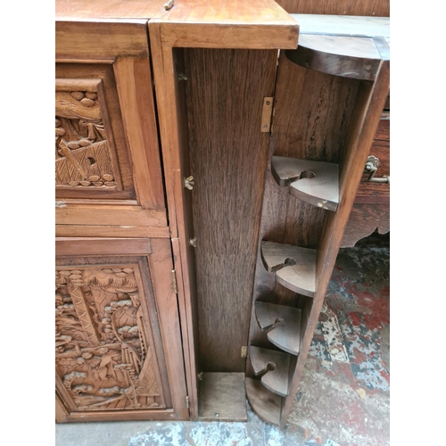 504 - An oriental carved teak concealed cocktail cabinet with hinged lid, eight place bottle holder, two l... 