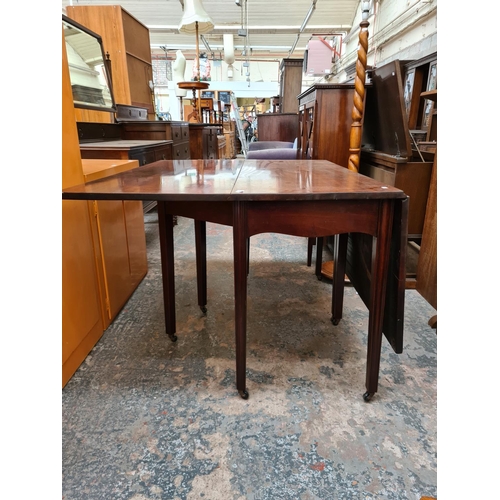 521 - A Georgian mahogany drop leaf gate legged dining table on eight tapered supports and later added cas... 