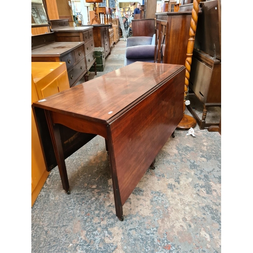 521 - A Georgian mahogany drop leaf gate legged dining table on eight tapered supports and later added cas... 