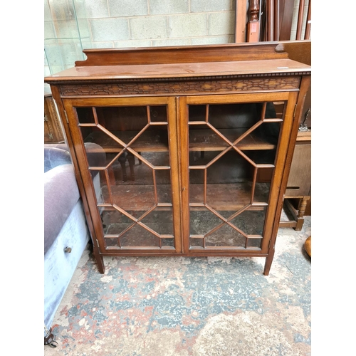 523 - An early 20th century mahogany display cabinet with carved fretwork top, two glazed doors and three ... 