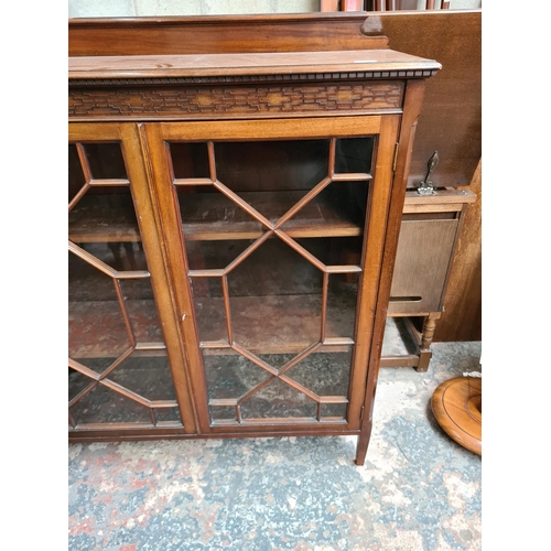 523 - An early 20th century mahogany display cabinet with carved fretwork top, two glazed doors and three ... 