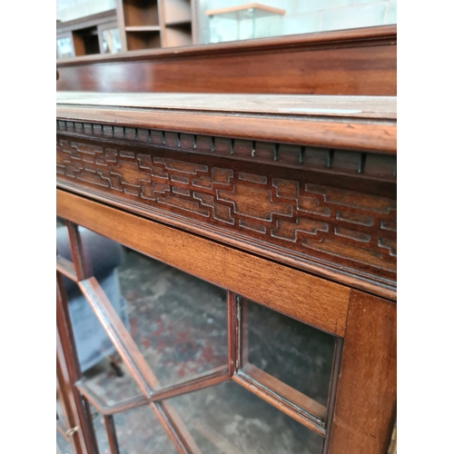 523 - An early 20th century mahogany display cabinet with carved fretwork top, two glazed doors and three ... 