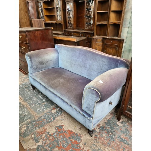 524 - A Victorian blue upholstered drop arm two seater sofa on castors - measuring approx. 163cm wide