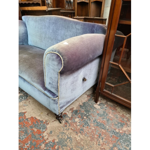 524 - A Victorian blue upholstered drop arm two seater sofa on castors - measuring approx. 163cm wide