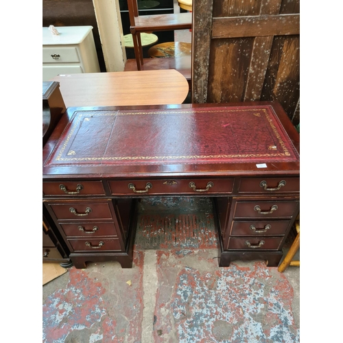 561 - A mahogany twin pedestal writing desk with eight outer drawers, one central drawer and red leather i... 