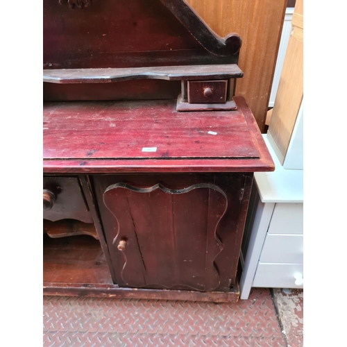 566 - A stained pine sideboard with one cupboard door, one long drawer and two further short drawers