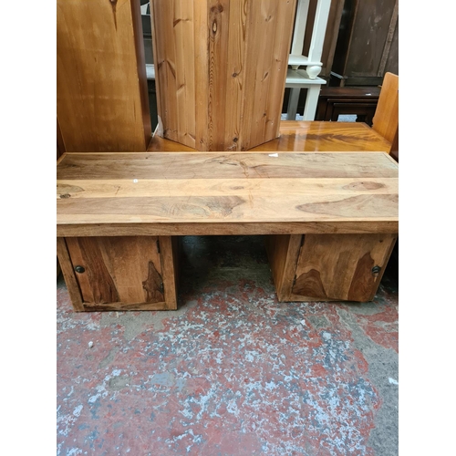 569 - An Indian sheesham wood coffee table with two lower cupboard doors - measuring approx. 140cm wide