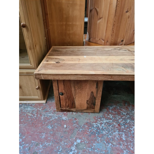 569 - An Indian sheesham wood coffee table with two lower cupboard doors - measuring approx. 140cm wide