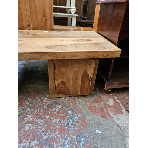 569 - An Indian sheesham wood coffee table with two lower cupboard doors - measuring approx. 140cm wide