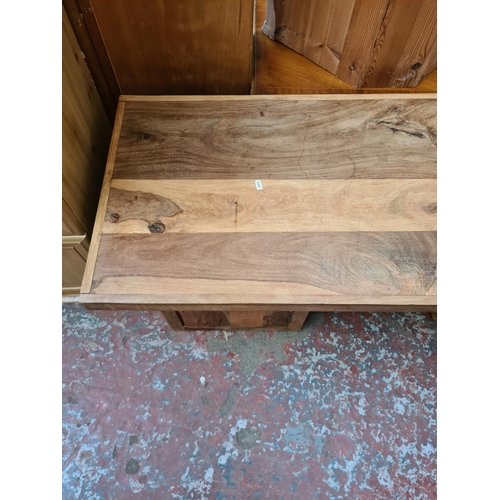 569 - An Indian sheesham wood coffee table with two lower cupboard doors - measuring approx. 140cm wide