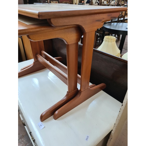 586 - A teak nest of two tables with tile inserts