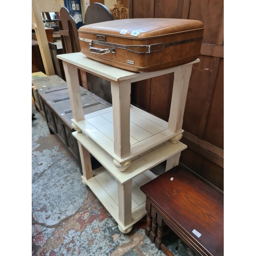 592 - A pair of white painted two tier side tables and a vintage brown American Tourister suitcase