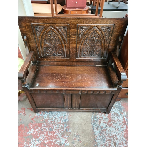 608 - An Arts and Crafts style oak monks bench with carved back and hinged seat - measuring approx. 103cm ... 