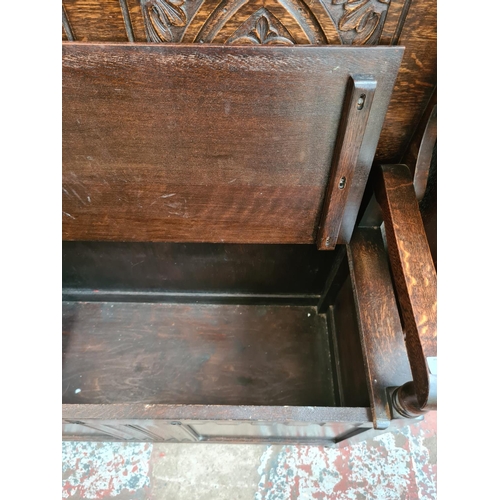 608 - An Arts and Crafts style oak monks bench with carved back and hinged seat - measuring approx. 103cm ... 