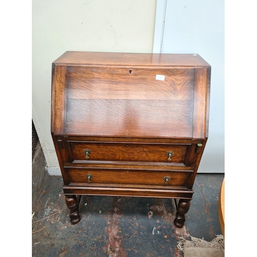 613 - A 1930s oak bureau on baluster supports with fall front and two drawers - measuring approx. 103cm hi... 