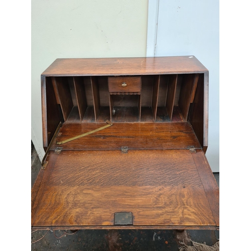 613 - A 1930s oak bureau on baluster supports with fall front and two drawers - measuring approx. 103cm hi... 