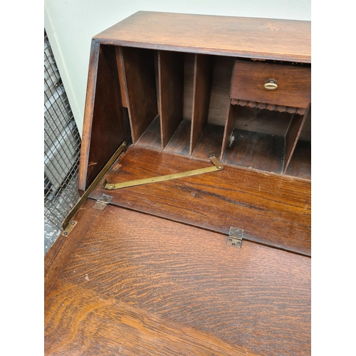 613 - A 1930s oak bureau on baluster supports with fall front and two drawers - measuring approx. 103cm hi... 