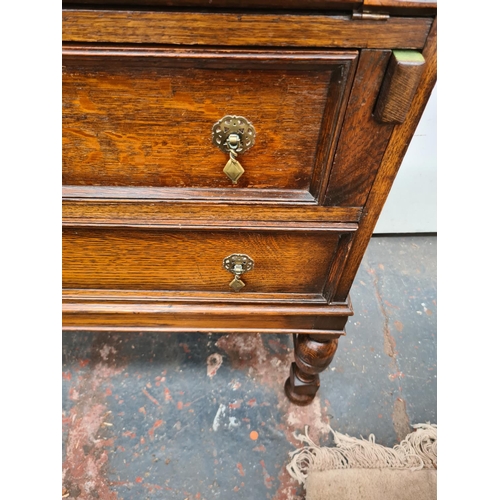 613 - A 1930s oak bureau on baluster supports with fall front and two drawers - measuring approx. 103cm hi... 