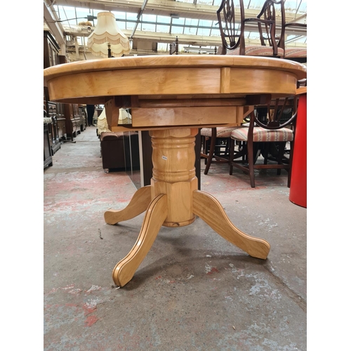 619 - A modern beech circular extending pedestal dining table - measuring approx. 75cm high and 107cm in d... 