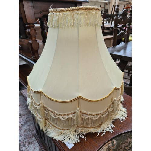 622 - An oak standard lamp with tassel shade and two spare shades