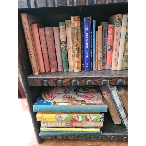 627 - An oak three tier bookcase containing a large quantity of vintage books to include Walt Disney's Sno... 