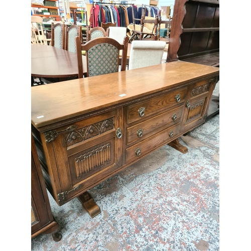 628 - An Old Charm oak sideboard with two outer cupboard doors and three central drawers - measuring appro... 