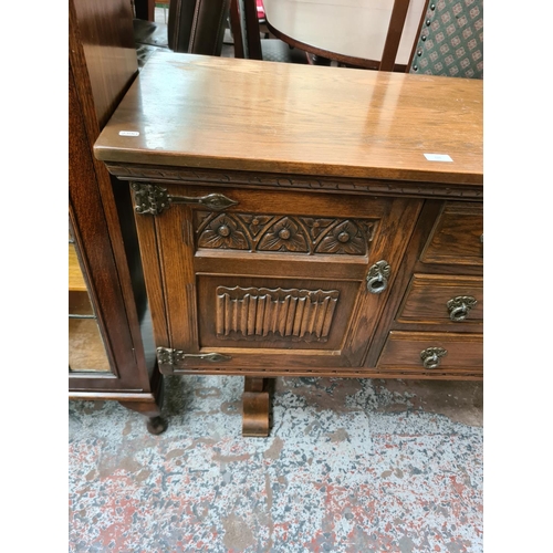 628 - An Old Charm oak sideboard with two outer cupboard doors and three central drawers - measuring appro... 