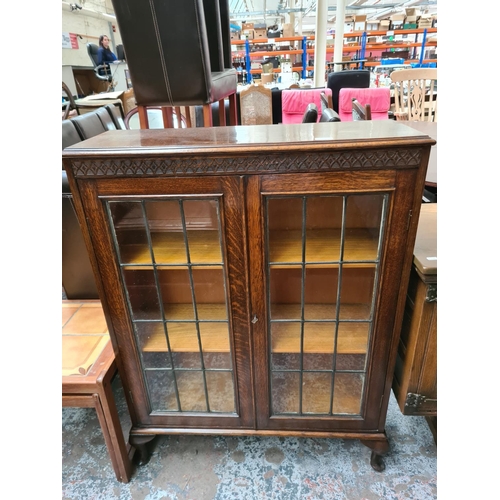 629 - An early 20th century oak bookcase on cabriole supports with two glazed doors and key - measuring ap... 