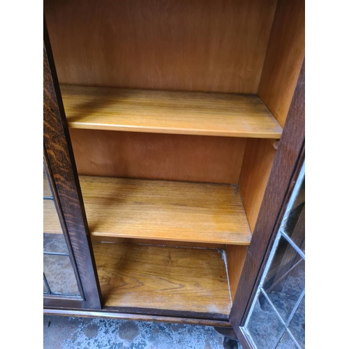 629 - An early 20th century oak bookcase on cabriole supports with two glazed doors and key - measuring ap... 