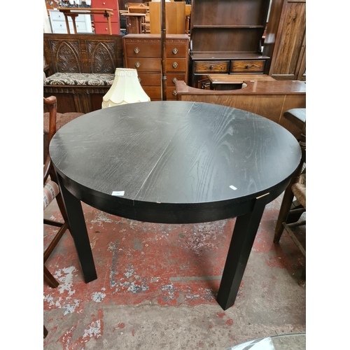 643 - A modern black ash extending circular dining table - measuring approx. 115cm in diameter (see condit... 