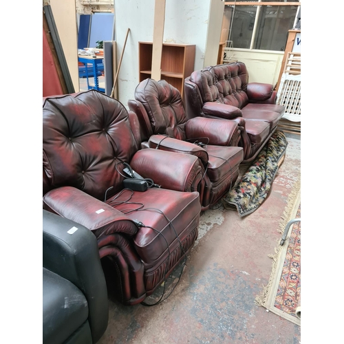 662B - An oxblood leather three piece lounge suite comprising three seater sofa and two reclining armchairs