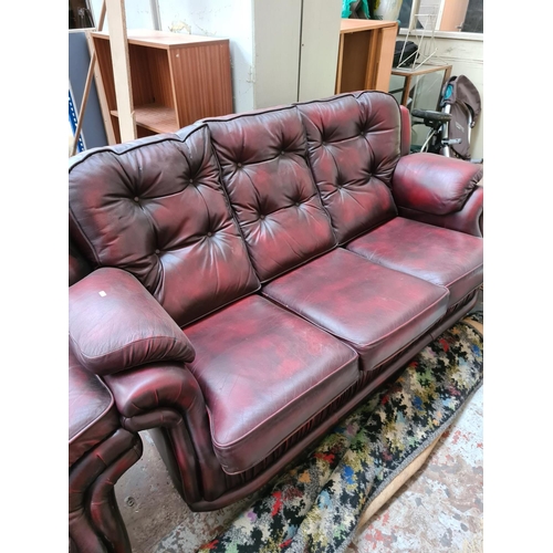 662B - An oxblood leather three piece lounge suite comprising three seater sofa and two reclining armchairs