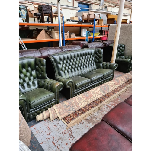 662C - A Chesterfield style green leather three piece lounge suite comprising three seater sofa and two arm... 