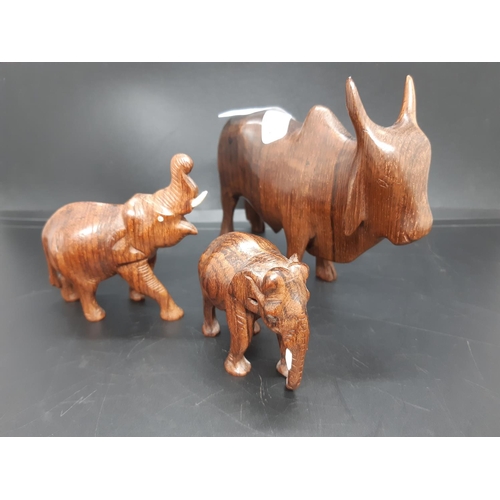 125 - Three carved treen animal figurines to include two elephants and a Zebu Bull