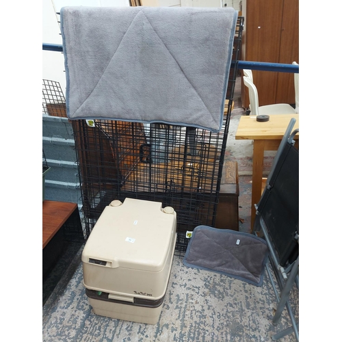 693 - Four items to include a large black metal folding dog cage, two pet blankets and a cream porte potty... 