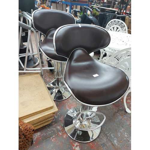 698 - A pair of brown vinyl high bar stools on gas powered chrome supports