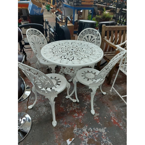 699 - A five piece cast aluminium white painted patio comprising of circular ornate table and four matchin... 