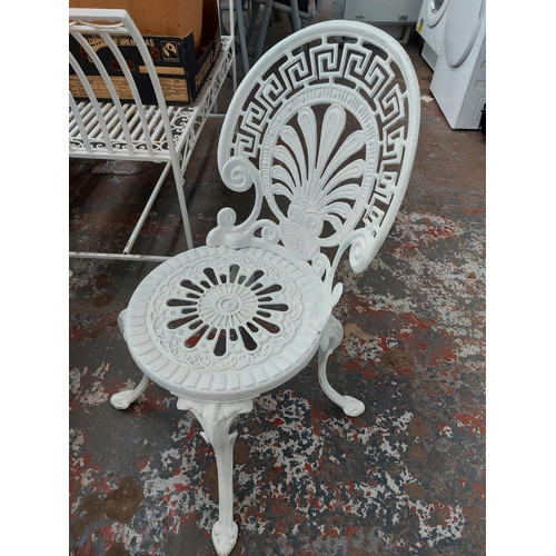 699 - A five piece cast aluminium white painted patio comprising of circular ornate table and four matchin... 