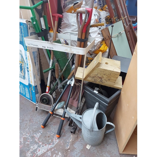 714 - A large mixed lot to include vintage galvanised watering can, wooden bird box, plastic planter, shov... 