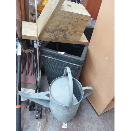 714 - A large mixed lot to include vintage galvanised watering can, wooden bird box, plastic planter, shov... 