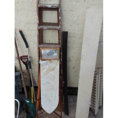 773 - Four items to include vintage wooden ironing board, 7 tread wooden step ladders and two black painte... 