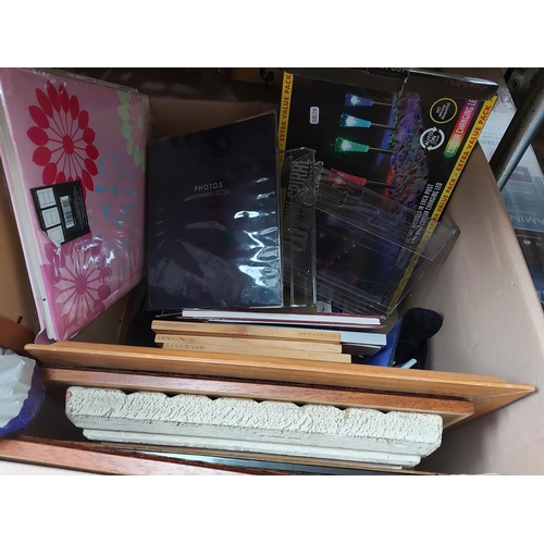 851 - A box containing picture frames, photo albums, garden lights, cast iron Christmas tree stands etc.