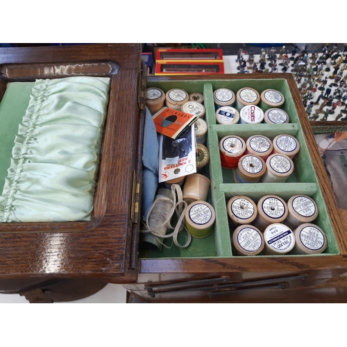 254 - A vintage oak cantilever sewing box on cabriole supports with brown ceramic castors and contents - m... 