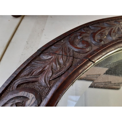 255 - An Arts and Crafts carved oak framed circular wall mirror believed to be Macclesfield School of Carv... 