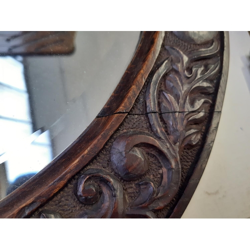 255 - An Arts and Crafts carved oak framed circular wall mirror believed to be Macclesfield School of Carv... 