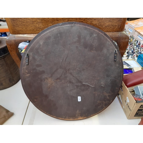 255 - An Arts and Crafts carved oak framed circular wall mirror believed to be Macclesfield School of Carv... 