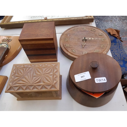 267 - Four pieces of treenware to include circular wall clock and three various lidded boxes